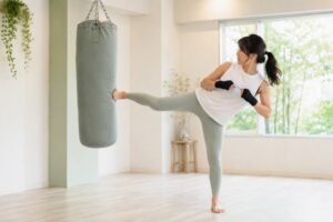 つくばのスタジオでサンドバッグにミドルキックを放つ女性。片脚立ちで体幹が安定している様子